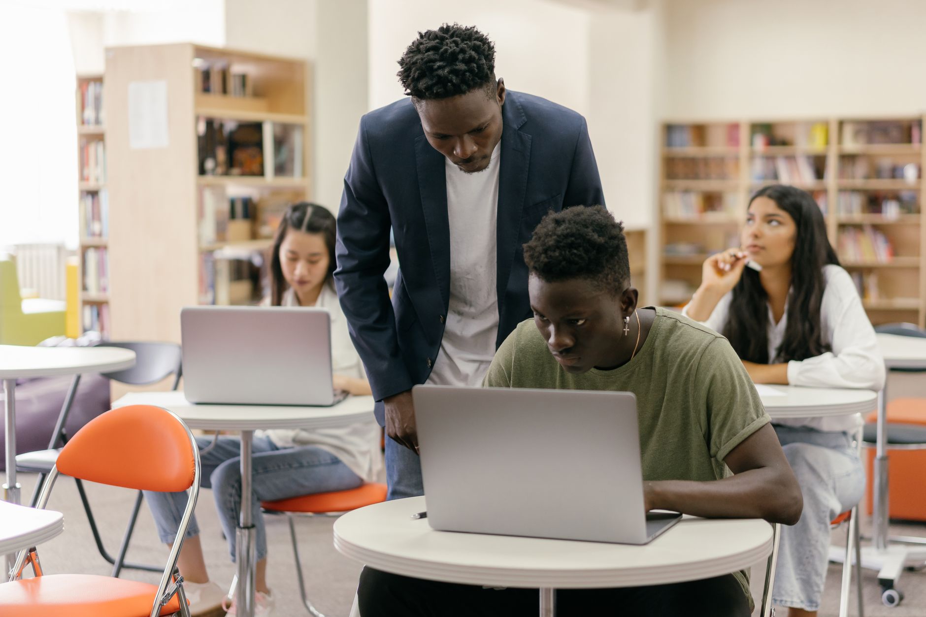 A teacher helping students working together in a bright classroom